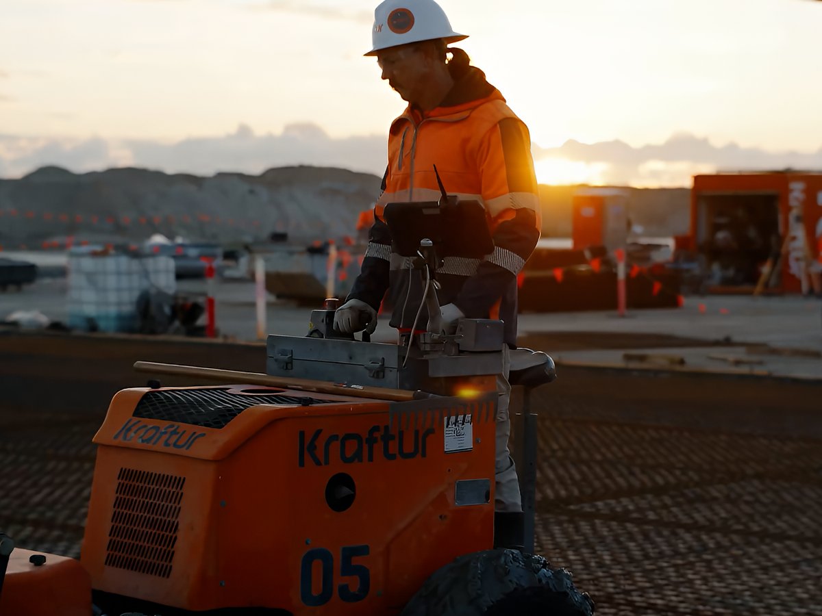 Construction videography on the Gold Coast capturing a site worker operating machinery at sunrise with industrial equipment and active works in the background.