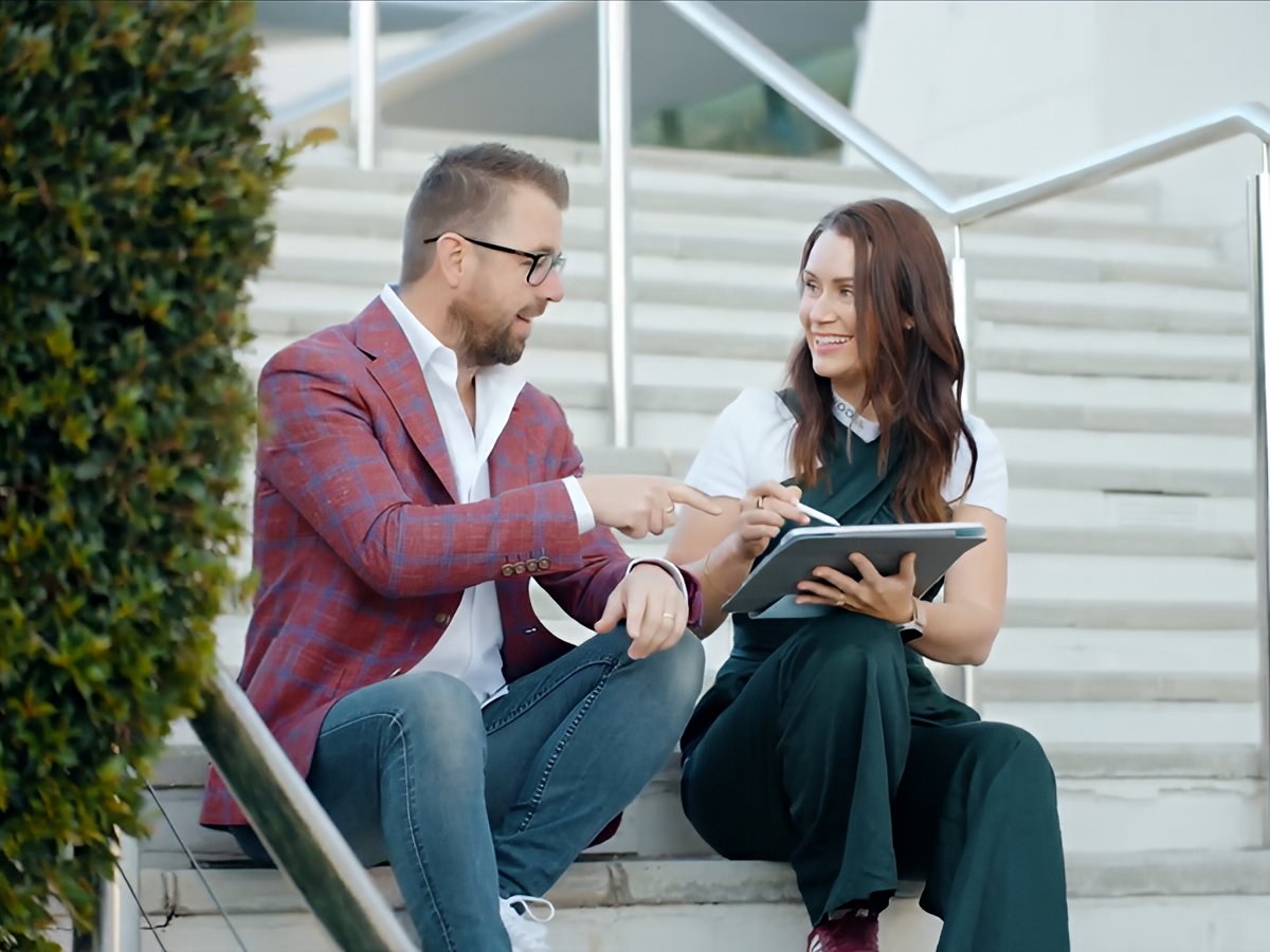 Corporate event videography on the Gold Coast capturing professionals in conversation during a business meeting with tablet collaboration and modern surroundings.
